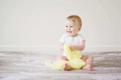 benefits of child adoption - picture of a baby playing and smiling | Minella Law