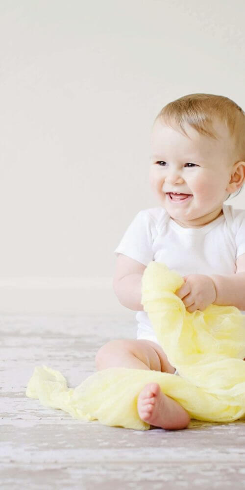 benefits of child adoption - picture of a baby playing and smiling | Minella Law