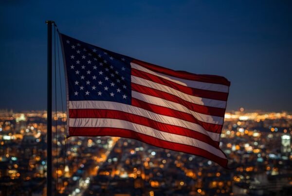American flag flying in a city at night